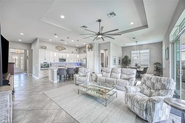 Tiled living room featuring a wealth of natural light, ceiling fan, and a raised ceiling