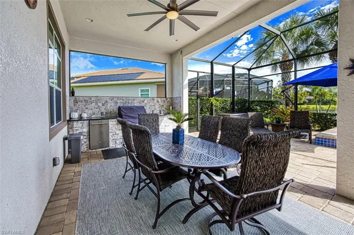 View of patio featuring ceiling fan, area for grilling, exterior kitchen, and a lanai