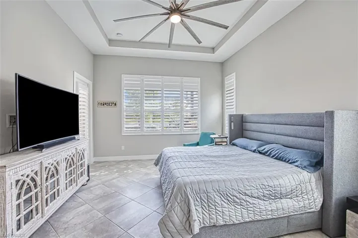 Tiled bedroom with ceiling fan and a raised ceiling
