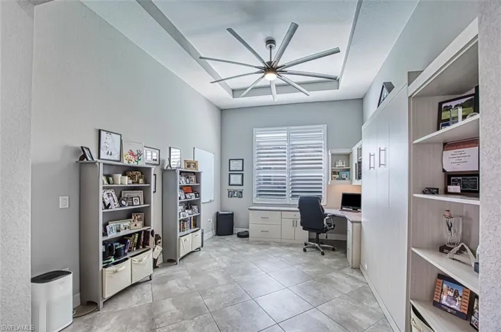 Tiled office space with ceiling fan and a raised ceiling