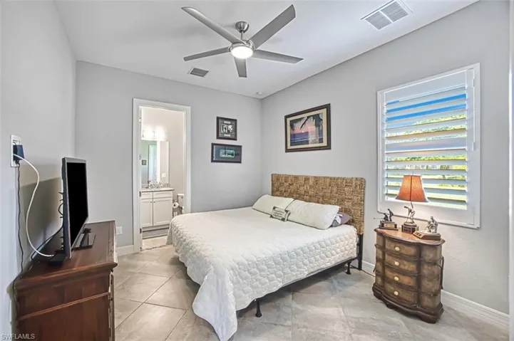 Bedroom with ceiling fan, ensuite bathroom, and light tile patterned floors