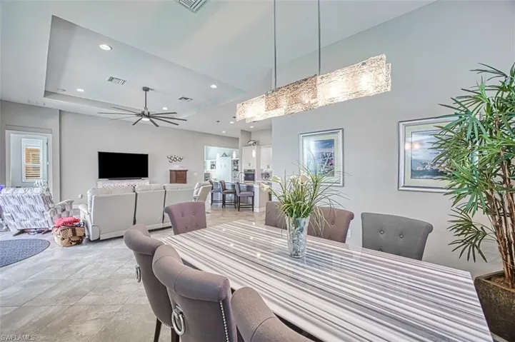 Dining space with a raised ceiling, ceiling fan, and light tile patterned flooring