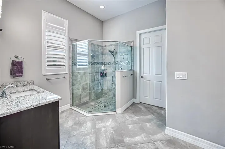 Bathroom featuring tile patterned floors, a shower with door, and vanity