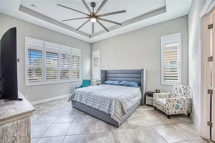 Bedroom featuring light tile patterned floors, multiple windows, and a tray ceiling