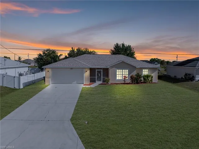 Single story home featuring concrete driveway, roof with shingles, an attached garage, a front yard, and fence
