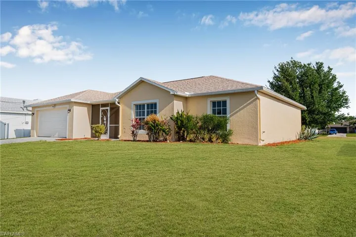 Ranch-style home featuring a front yard, driveway, a garage, and stucco siding