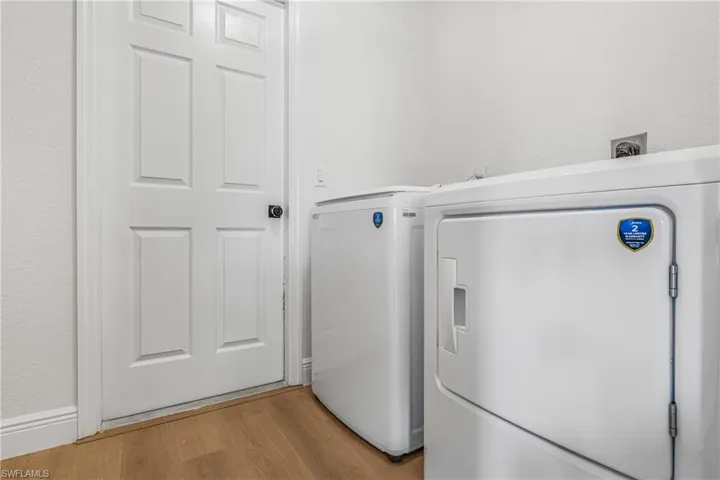 Clothes washing area with washer and dryer, light wood-style floors, and laundry area