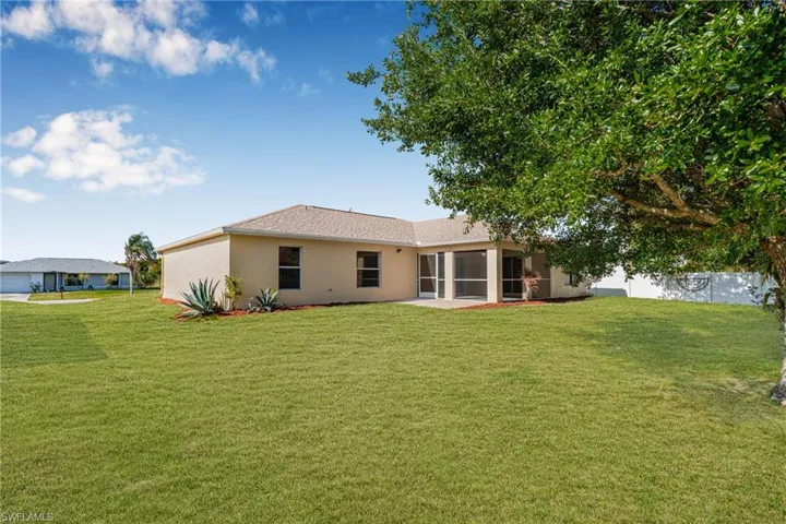 Back of property with a sunroom, a yard, and stucco siding