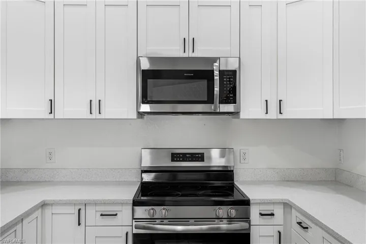 Kitchen featuring white cabinetry and appliances with stainless steel finishes