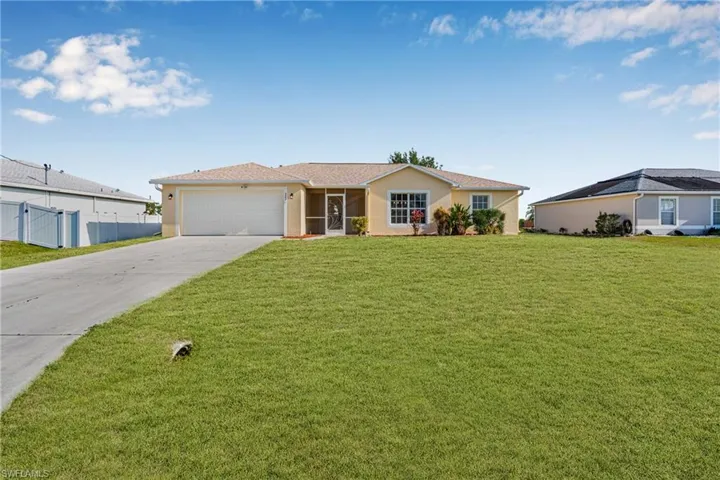 Ranch-style home featuring driveway, stucco siding, an attached garage, and a front lawn