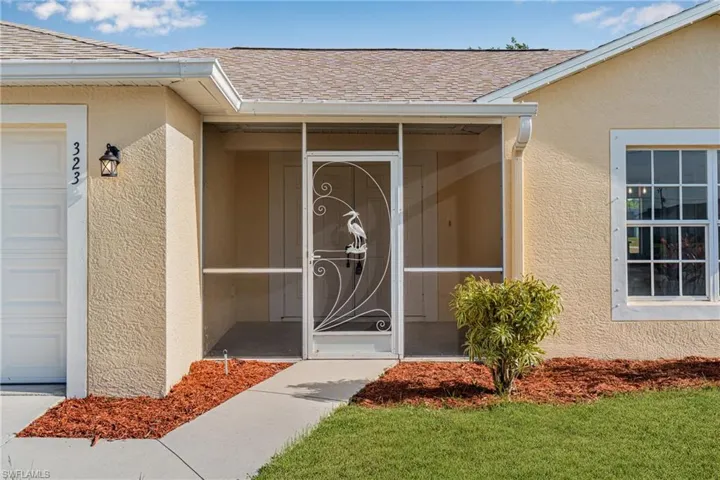 View of exterior entry with stucco siding and a shingled roof