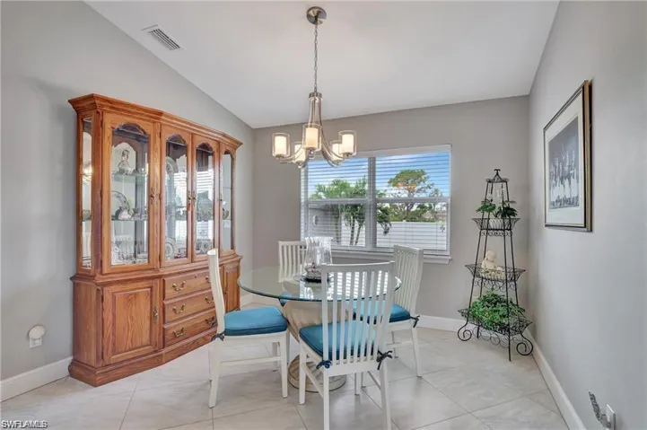 Tiled dining room featuring lofted ceiling and a notable chandelier