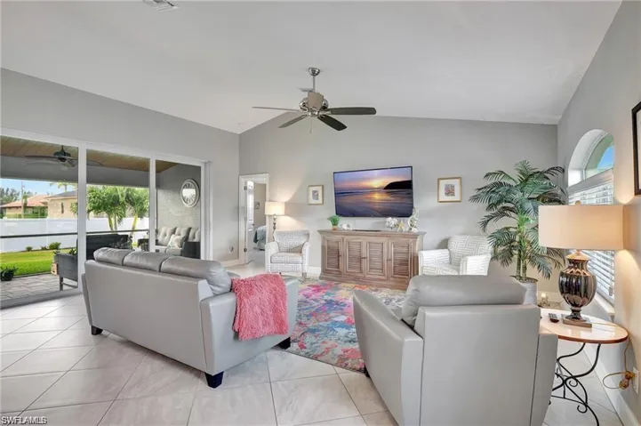 Living room featuring plenty of natural light, vaulted ceiling, light tile patterned floors, and ceiling fan