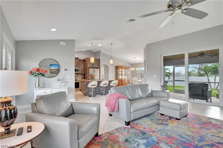 Living room with vaulted ceiling, sink, light tile patterned floors, and ceiling fan