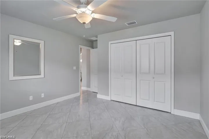 Unfurnished bedroom with a closet, light tile patterned floors, and ceiling fan