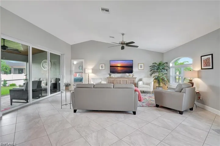 Tiled living room featuring ceiling fan and vaulted ceiling
