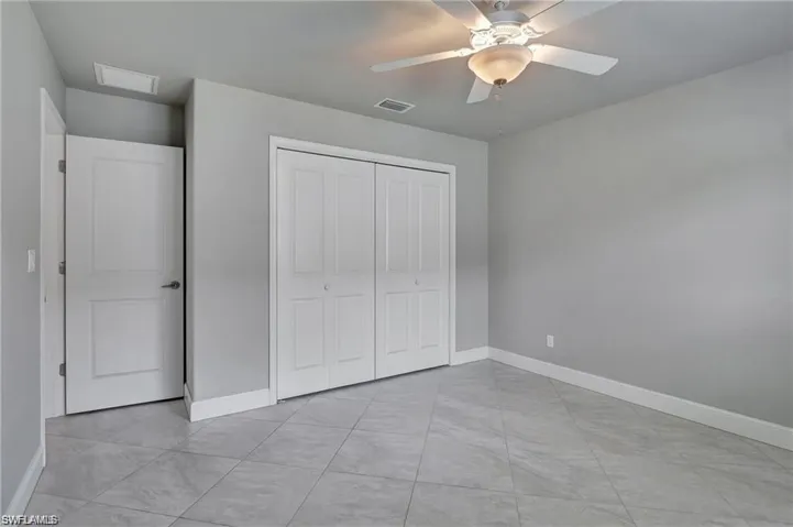 Unfurnished bedroom featuring a closet, ceiling fan, and light tile patterned floors