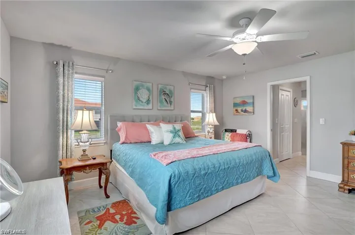 Tiled bedroom with multiple windows and ceiling fan