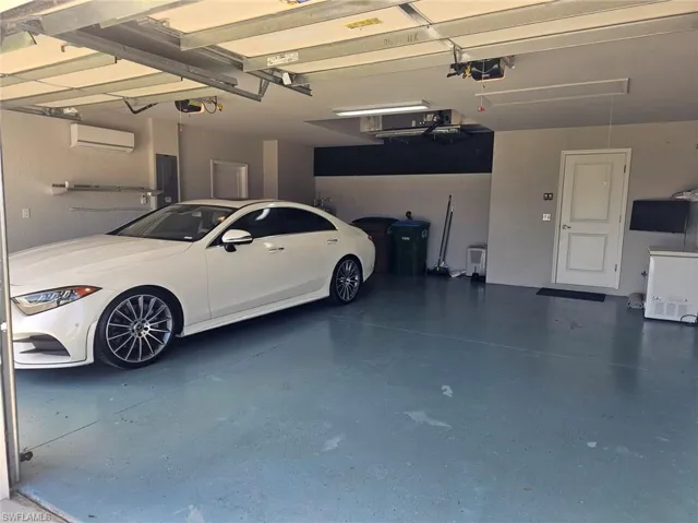 Garage featuring a wall mounted AC, electric panel, and a garage door opener