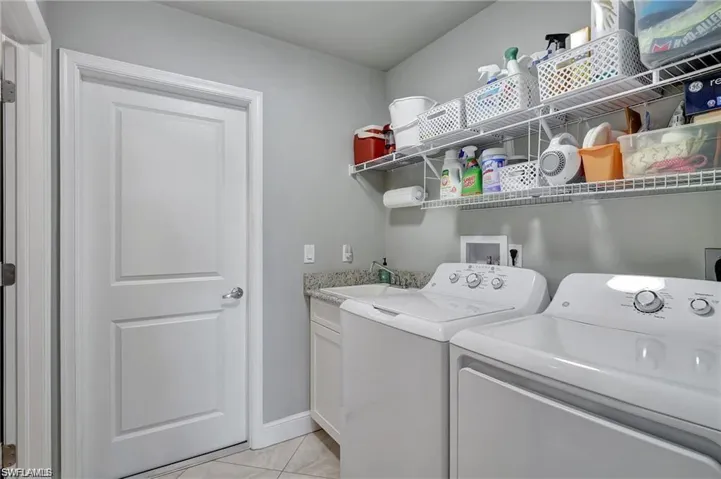 Clothes washing area with light tile patterned flooring, sink, and independent washer and dryer