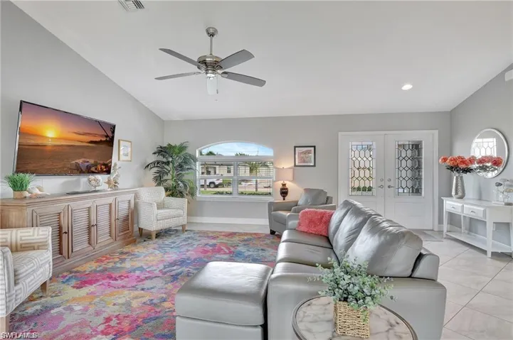 Living room featuring french doors, light tile patterned floors, ceiling fan, and vaulted ceiling