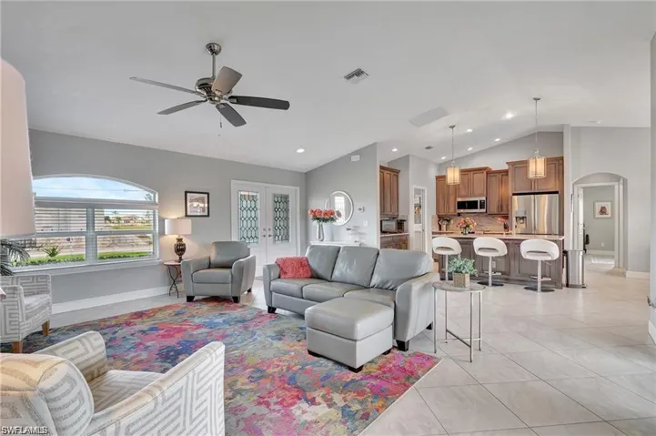 Living room with light tile patterned floors, ceiling fan, and vaulted ceiling