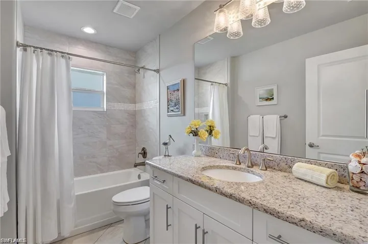 Full bathroom with vanity, shower / bath combo with shower curtain, tile patterned flooring, and toilet