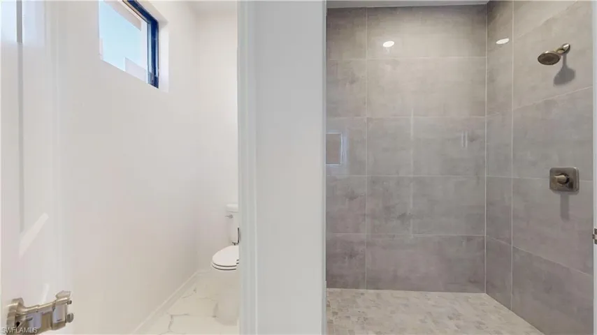 Full bath featuring a stall shower and marble look tile flooring
