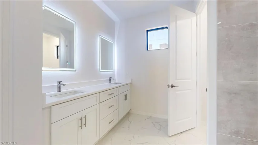 Full bathroom featuring double vanity and light marble finish floors