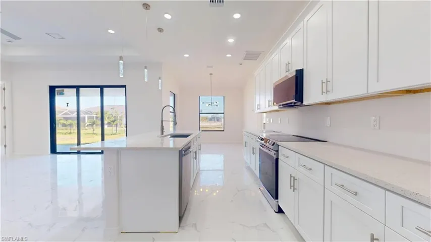 Kitchen featuring stainless steel appliances, recessed lighting, hanging light fixtures, light stone counters, and plenty of natural light
