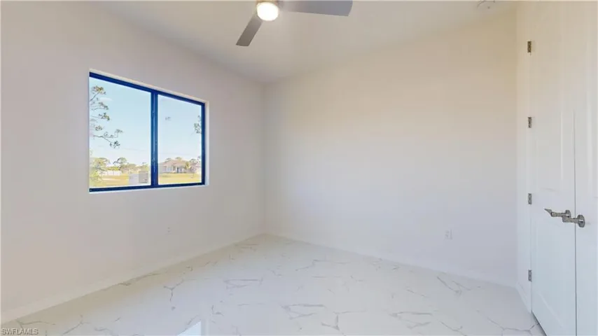 Unfurnished room featuring light marble finish floors and a ceiling fan