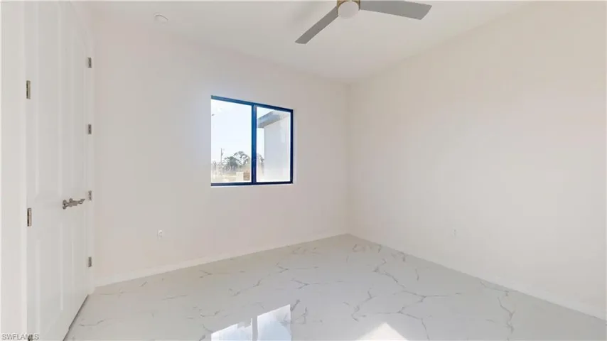 Empty room with marble look tile flooring and ceiling fan
