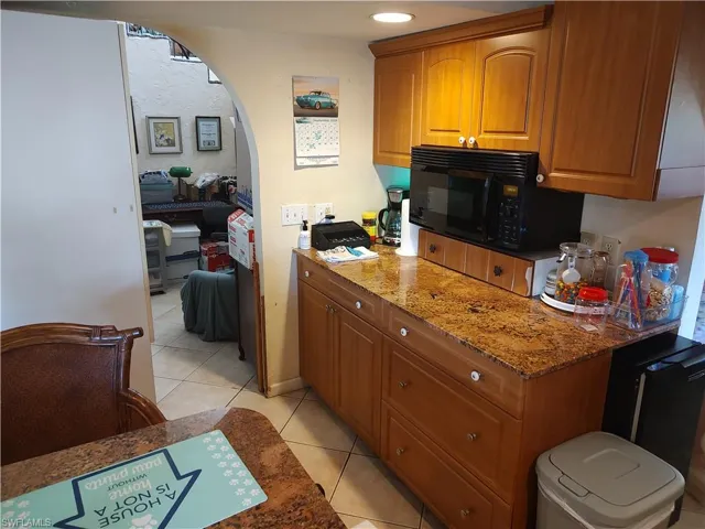 Kitchen with light tile patterned flooring and stone counters