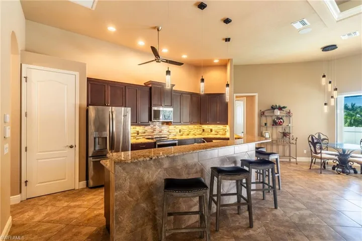 Kitchen with stainless steel appliances, dark brown cabinetry, tasteful backsplash, a kitchen bar, and decorative light fixtures