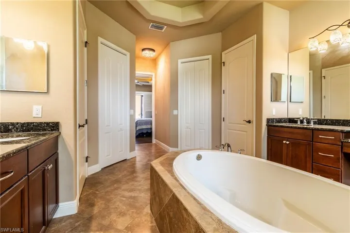 Bathroom with vanity, tiled tub, and tile patterned floors