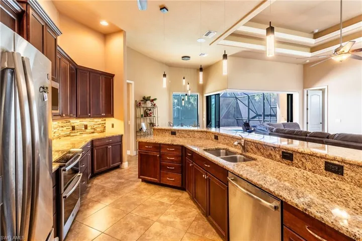 Kitchen featuring stainless steel appliances, hanging light fixtures, sink, and a high ceiling
