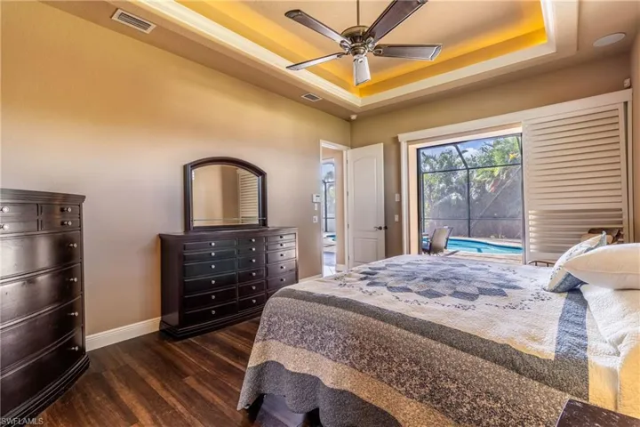 Bedroom featuring dark hardwood / wood-style flooring, ceiling fan, and a raised ceiling