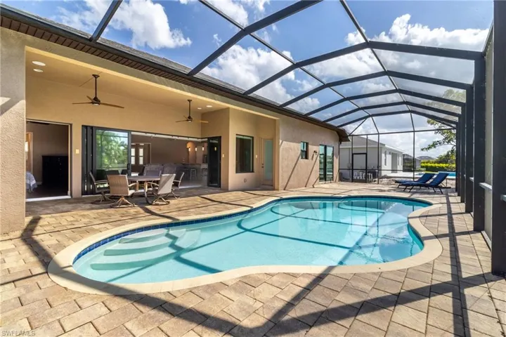View of swimming pool featuring ceiling fan, a patio, and a lanai