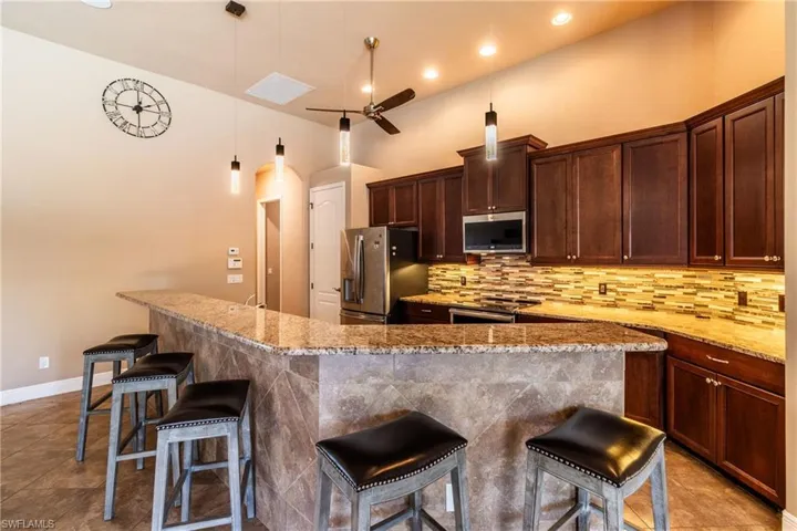 Kitchen featuring pendant lighting, appliances with stainless steel finishes, ceiling fan, and a breakfast bar