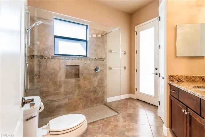 Bathroom with toilet, vanity, tile patterned flooring, and tiled shower
