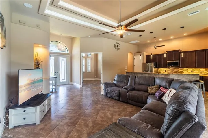 Living room featuring dark tile patterned floors, a tray ceiling, ceiling fan, and a towering ceiling