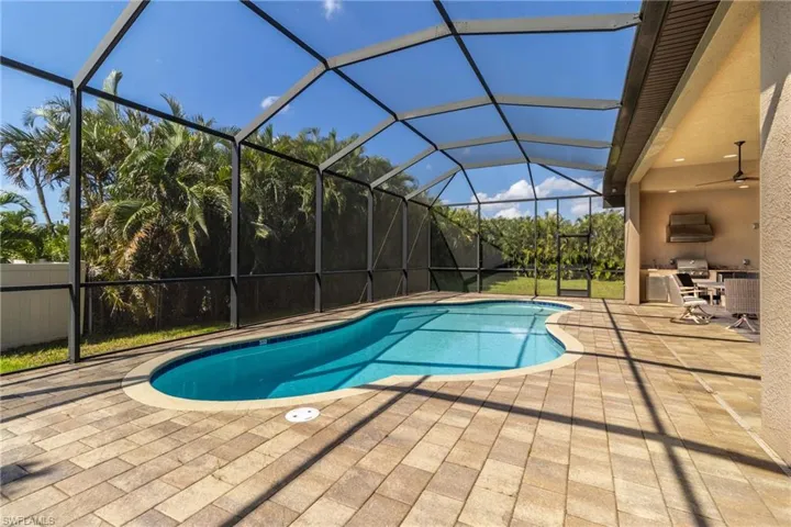 View of swimming pool featuring glass enclosure, a patio, and ceiling fan