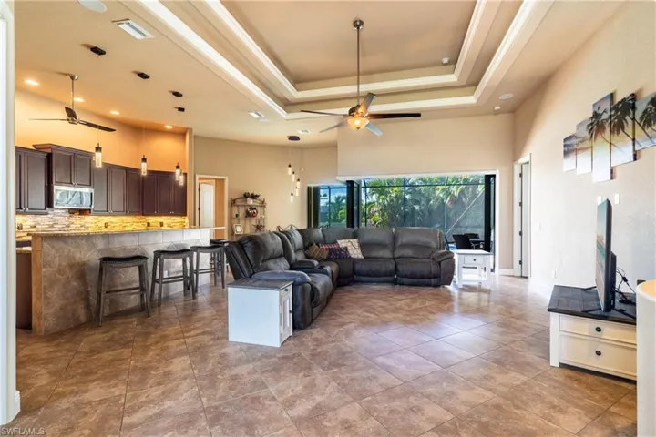 Tiled living room featuring a towering ceiling, ceiling fan, and a raised ceiling
