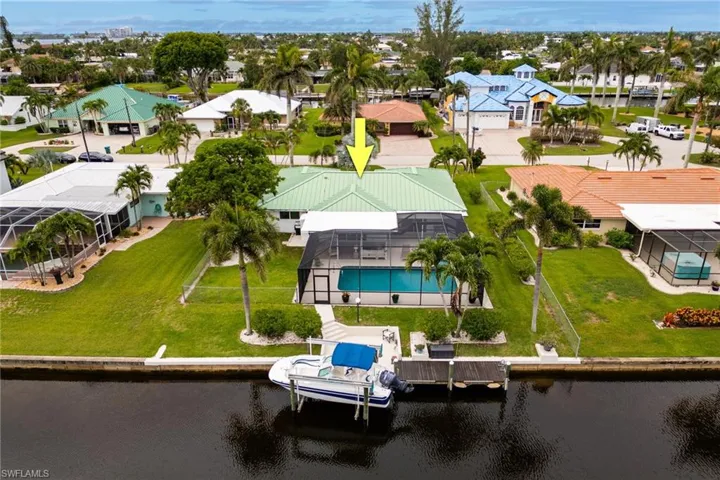 Rear aerial view showing large fenced yard, dock and lift