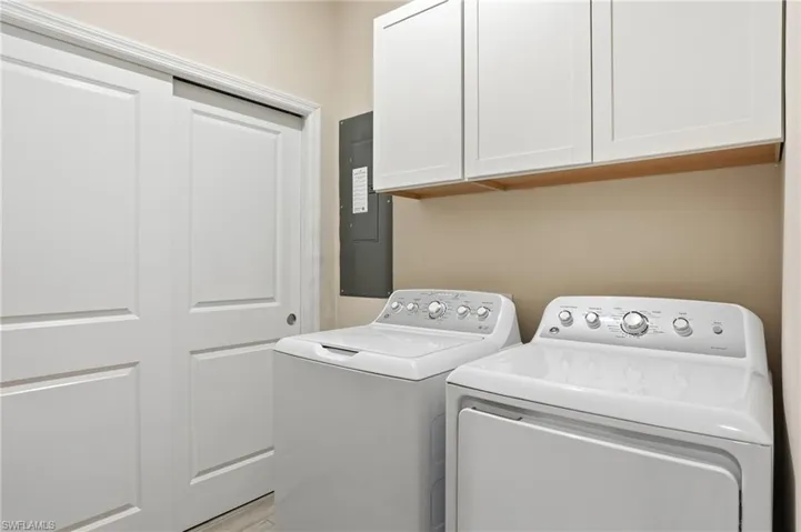 Laundry area with electric panel, washing machine and dryer, and cabinet space