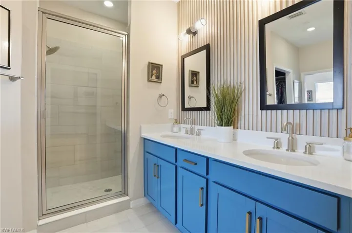Bathroom with double vanity, a shower stall, recessed lighting, light tile patterned flooring, and wallpapered walls
