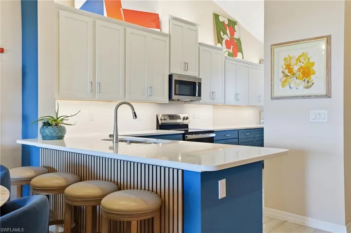 Kitchen with a breakfast bar, a peninsula, stainless steel appliances, and tasteful backsplash