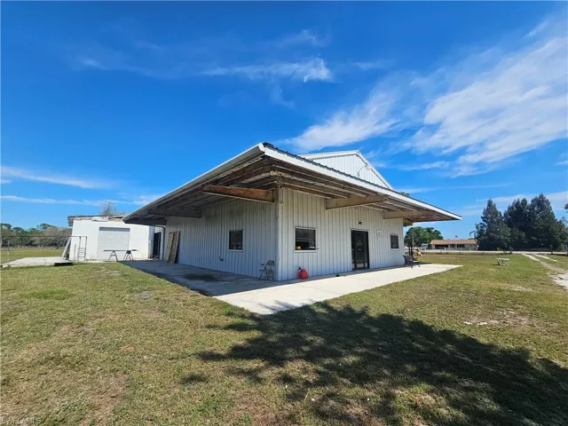 Rear view of property featuring a patio area, metal roof, and a yard