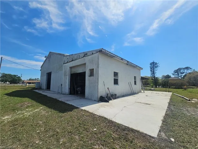 View of side of property with a garage, a lawn, concrete driveway, an outbuilding, and stucco siding
