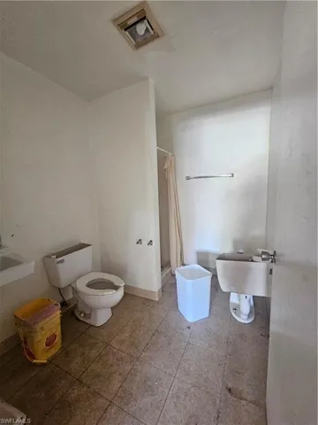 Full bathroom with toilet, a shower with shower curtain, a sink, and visible vents